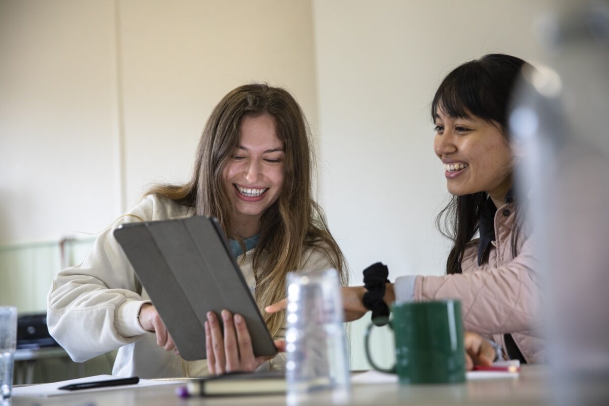 Two women smiling looking at an iPad